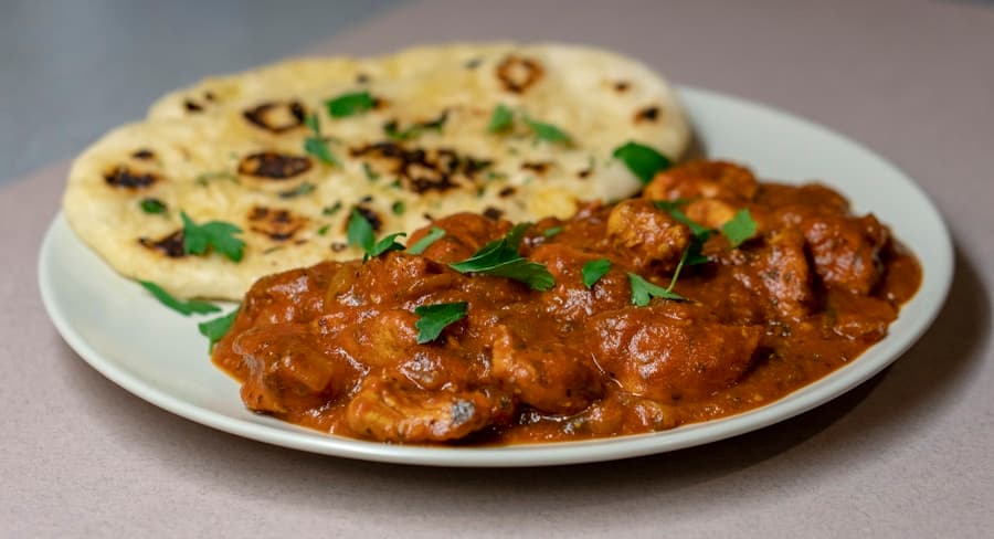 Yakhni — pale yoghurt-braised mutton in white ceramic, side light, editorial presentation